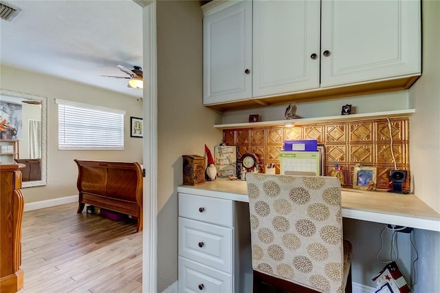 bar featuring white cabinetry, light hardwood / wood-style flooring, ceiling fan, and built in desk