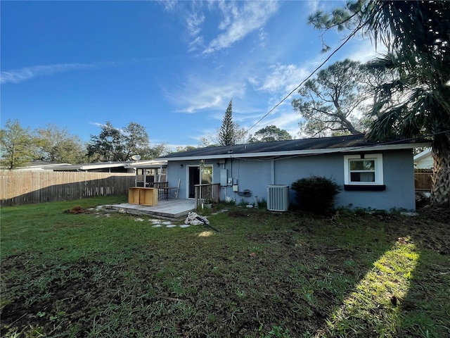 rear view of house featuring central AC and a lawn