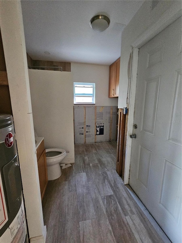 bathroom with hardwood / wood-style flooring, toilet, vanity, and washer / clothes dryer