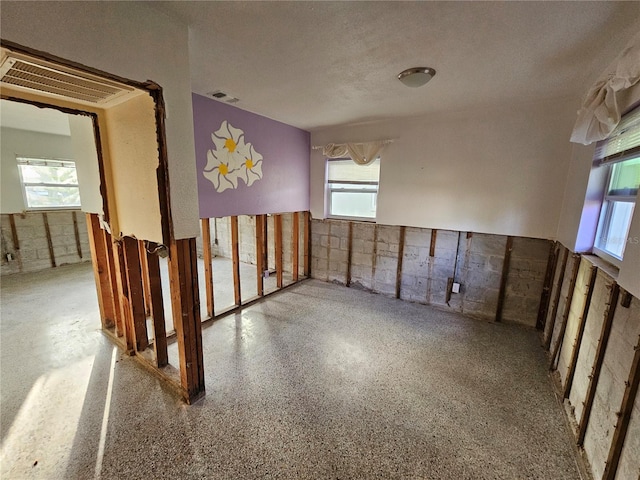 unfurnished room with a textured ceiling and a healthy amount of sunlight