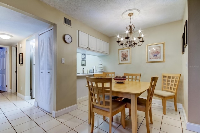 tiled dining area with a notable chandelier and a textured ceiling