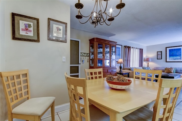 dining area featuring a notable chandelier, a textured ceiling, and light tile patterned floors