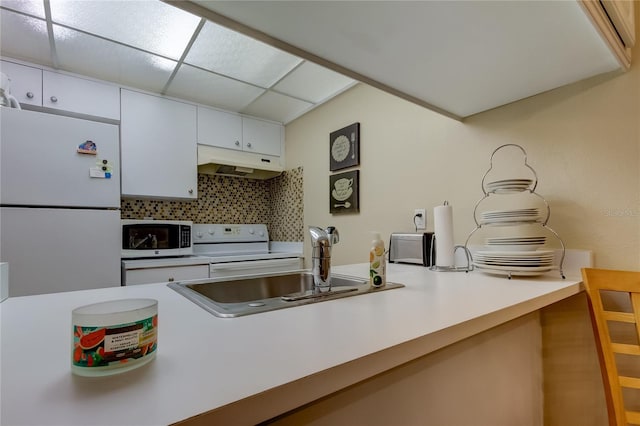 kitchen featuring white appliances, tasteful backsplash, sink, white cabinetry, and a paneled ceiling