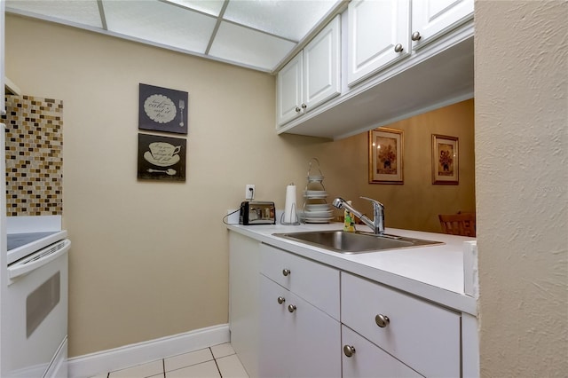 kitchen featuring white cabinets, sink, light tile patterned floors, and white stove