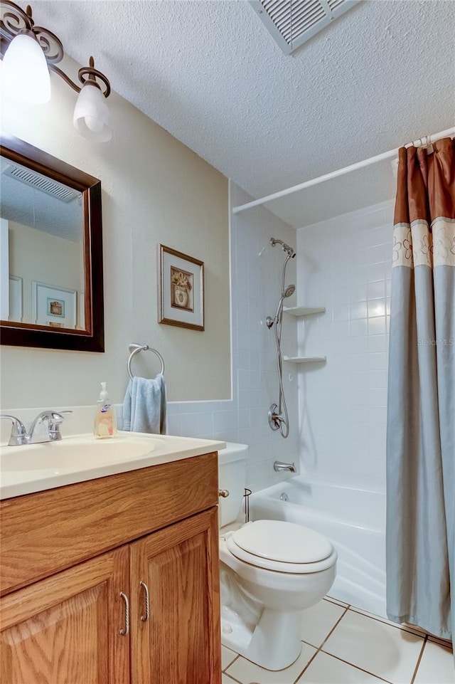 full bathroom with tile patterned floors, toilet, shower / bath combo with shower curtain, vanity, and a textured ceiling