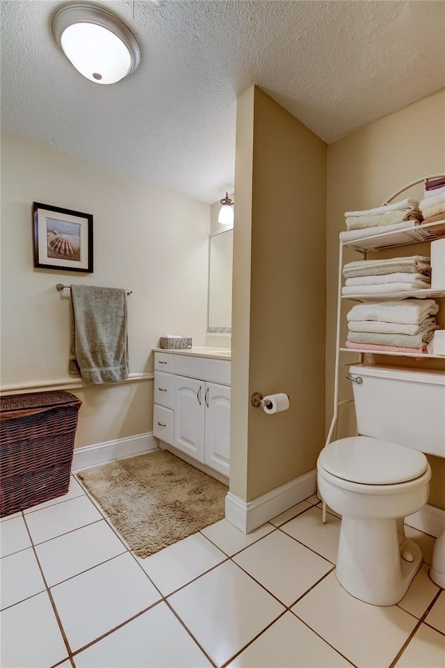 bathroom with vanity, toilet, tile patterned floors, and a textured ceiling