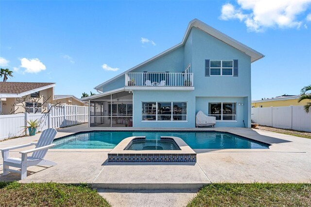 rear view of property featuring a patio, a pool with hot tub, a sunroom, and a balcony