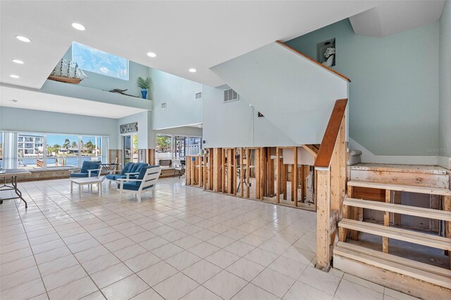 tiled living room featuring a skylight and a high ceiling