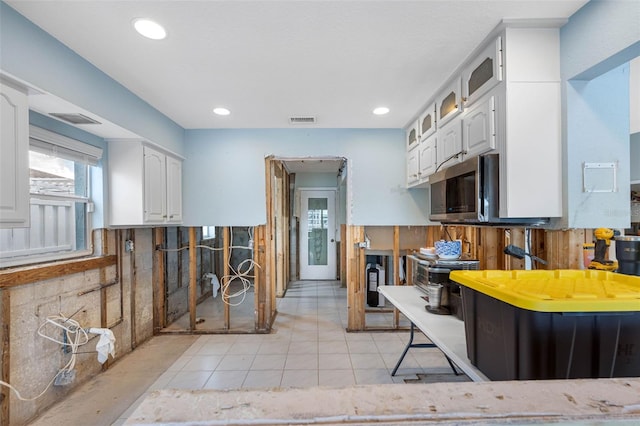 kitchen with white cabinetry, backsplash, and light tile patterned floors