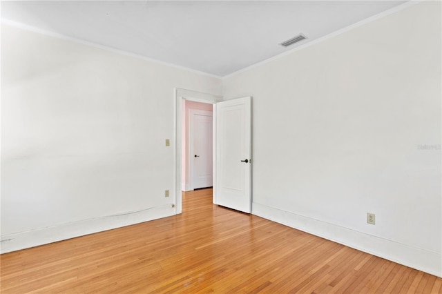 empty room featuring light hardwood / wood-style floors and crown molding