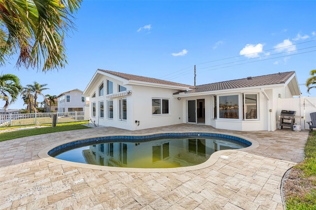 rear view of house featuring a fenced in pool and a patio