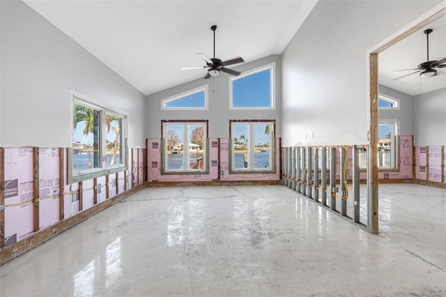 empty room with high vaulted ceiling, ceiling fan, and concrete floors