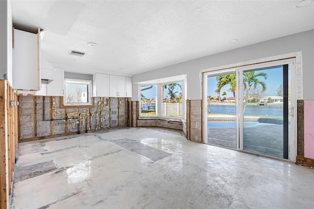 spare room featuring a textured ceiling and a water view