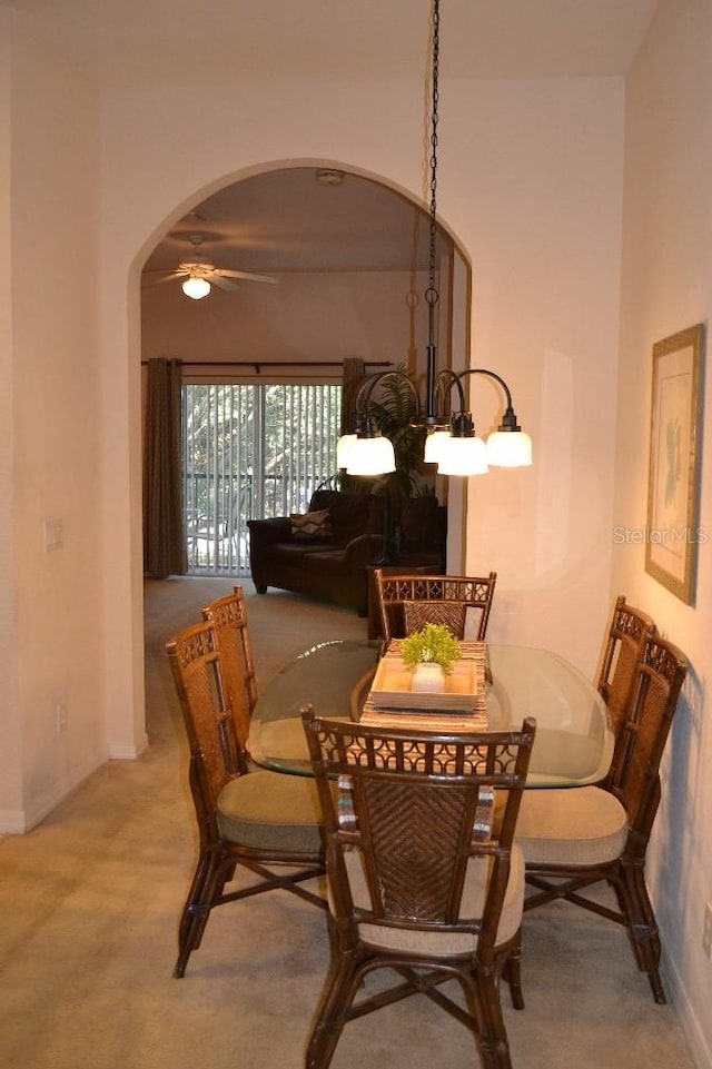 carpeted dining area featuring ceiling fan with notable chandelier