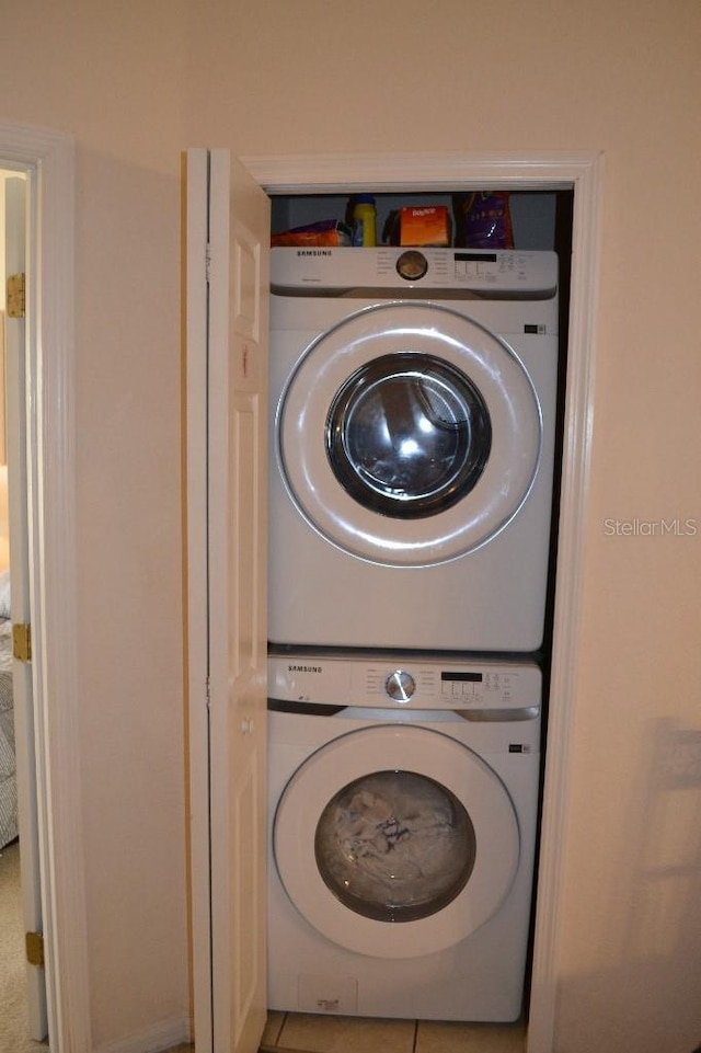 laundry area with tile patterned flooring and stacked washer / dryer