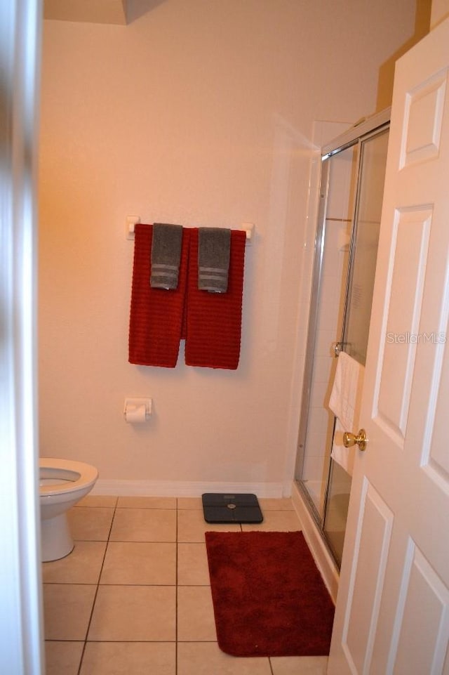 bathroom featuring walk in shower, tile patterned floors, and toilet