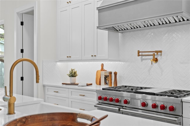 kitchen featuring decorative backsplash, custom range hood, range with two ovens, and white cabinets