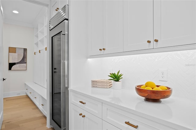 interior space with decorative backsplash, high end refrigerator, and white cabinets