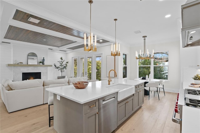 kitchen with gray cabinets, sink, stainless steel dishwasher, a center island with sink, and light wood-type flooring