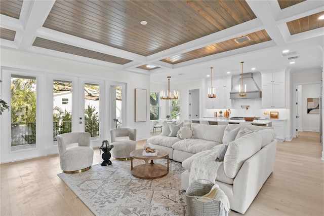 living room with coffered ceiling, a wealth of natural light, and light hardwood / wood-style flooring