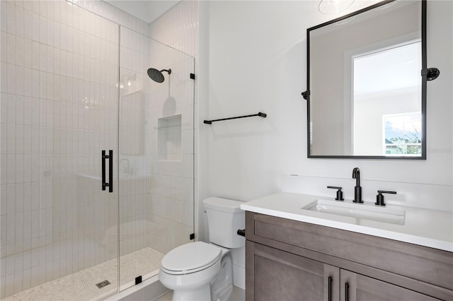 bathroom with toilet, vanity, and a shower with shower door