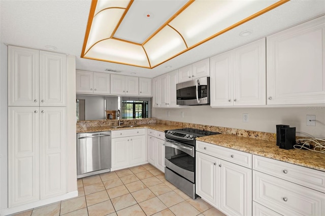 kitchen featuring white cabinets, light stone counters, light tile patterned floors, appliances with stainless steel finishes, and sink