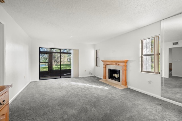 unfurnished living room with a healthy amount of sunlight, a textured ceiling, and dark carpet