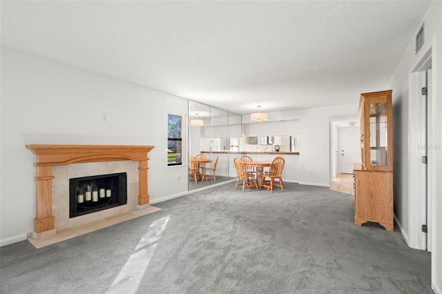 unfurnished living room with a textured ceiling, a tiled fireplace, and dark colored carpet