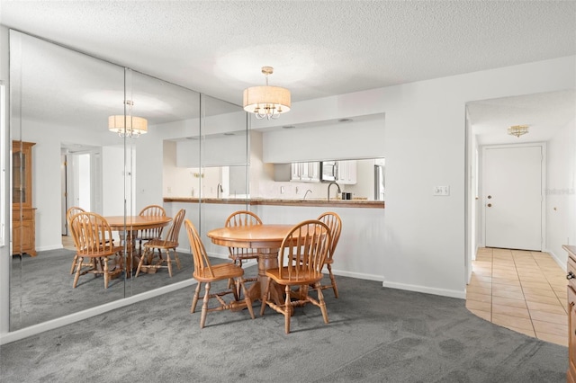 dining room featuring a textured ceiling, a chandelier, and carpet