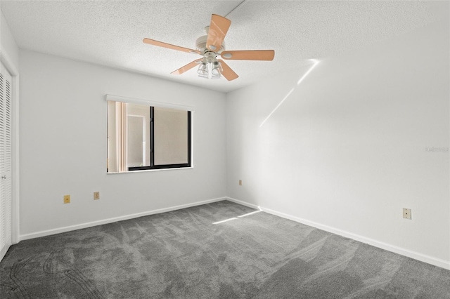 empty room featuring dark carpet, a textured ceiling, and ceiling fan