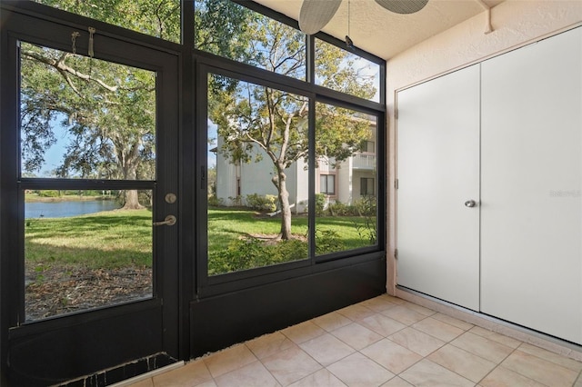 doorway to outside with a textured ceiling, a water view, and light tile patterned floors