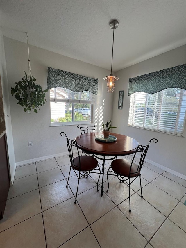 dining space with a healthy amount of sunlight, a textured ceiling, and light tile patterned floors