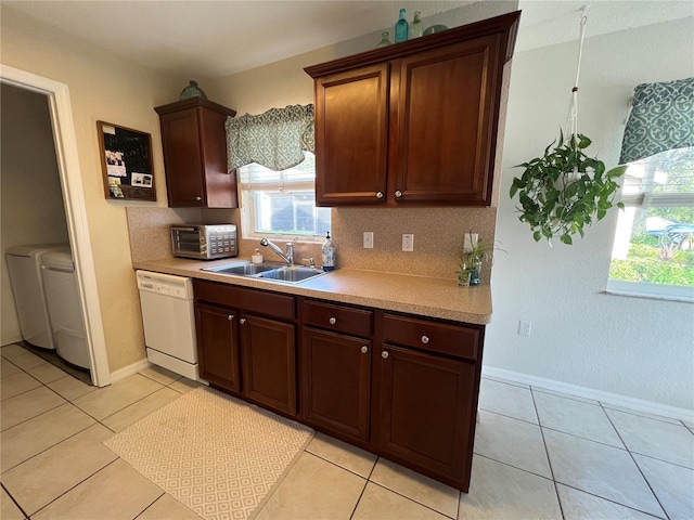 kitchen with light tile patterned flooring, dishwasher, sink, and washing machine and clothes dryer