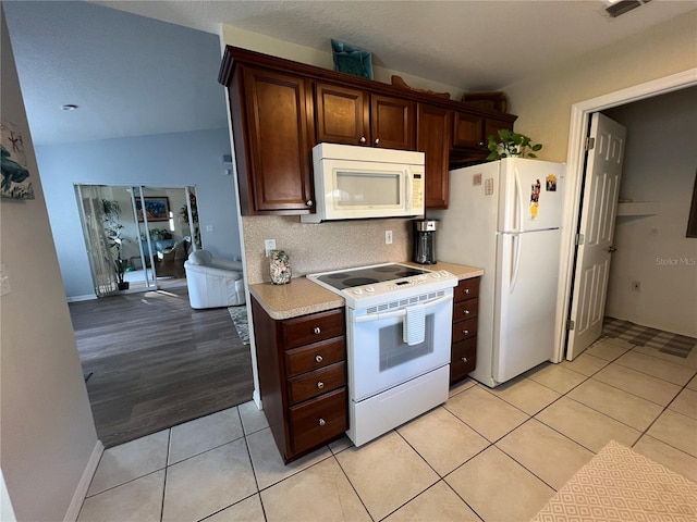 kitchen featuring light hardwood / wood-style floors, lofted ceiling, and white appliances