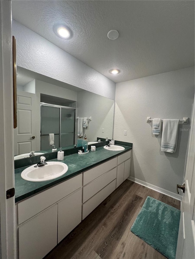 bathroom with vanity, a textured ceiling, hardwood / wood-style flooring, and a shower with shower door