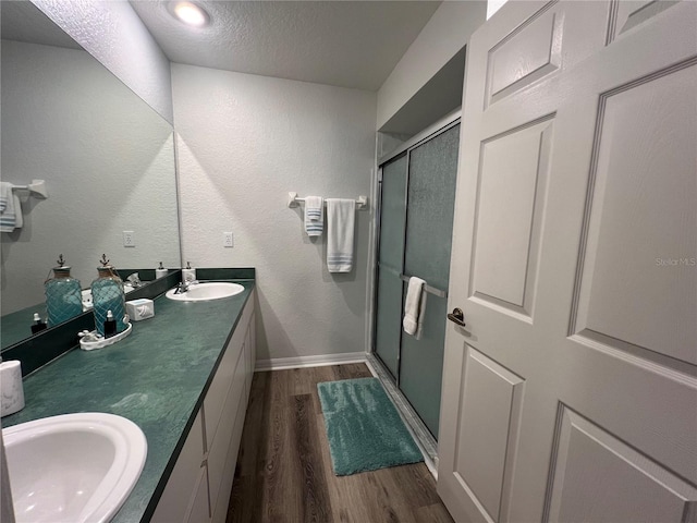 bathroom with vanity, an enclosed shower, a textured ceiling, and wood-type flooring