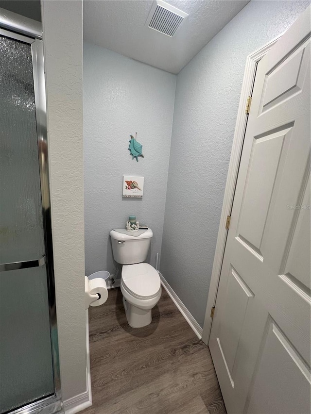 bathroom with a shower with door, toilet, and hardwood / wood-style floors