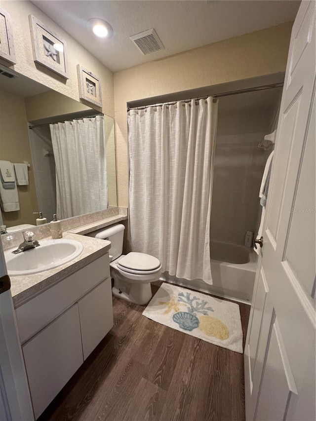 full bathroom featuring vanity, toilet, hardwood / wood-style flooring, and shower / bath combo with shower curtain