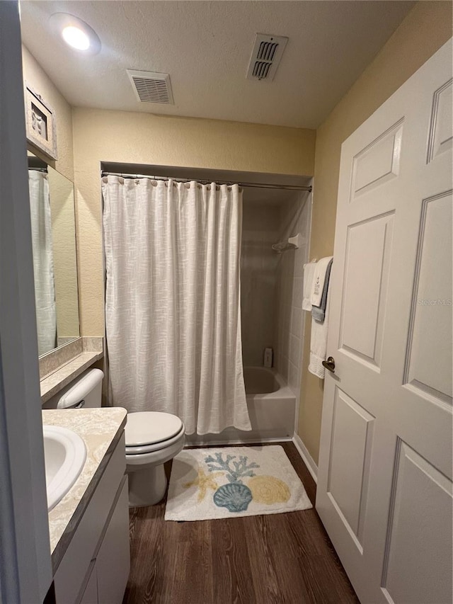 full bathroom with shower / bath combination with curtain, a textured ceiling, hardwood / wood-style flooring, toilet, and vanity