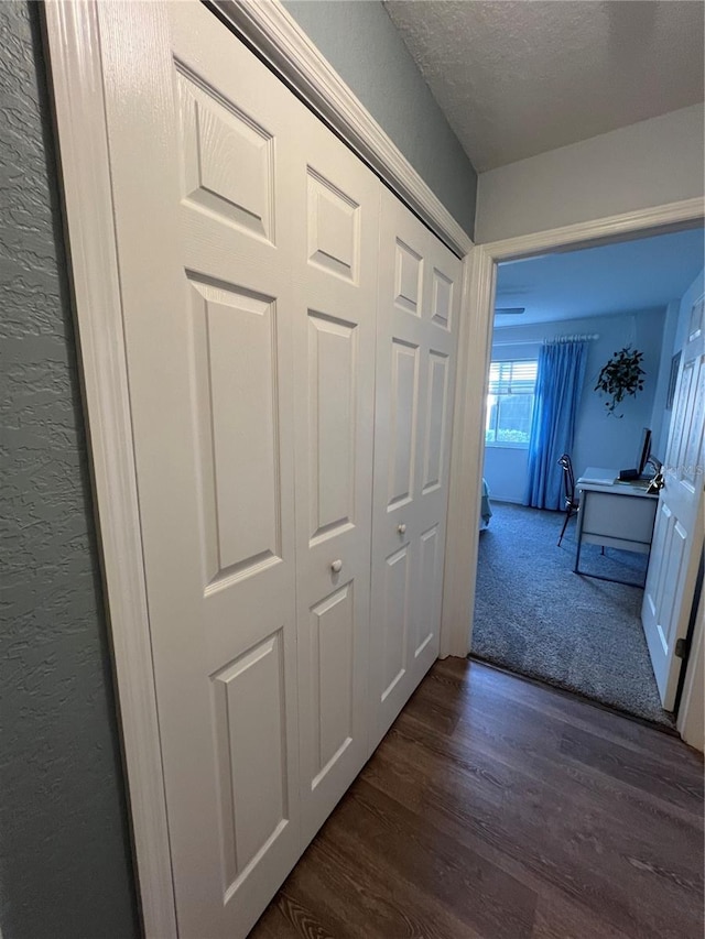 hallway with a textured ceiling and dark hardwood / wood-style floors