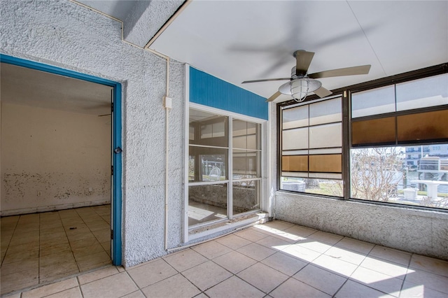 unfurnished sunroom with ceiling fan