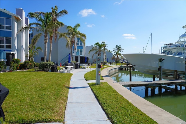 surrounding community featuring a yard, a water view, boat lift, and a dock