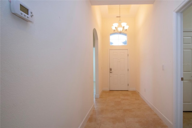 entryway featuring a towering ceiling, light tile patterned floors, and a chandelier