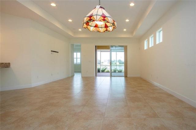 tiled empty room with a tray ceiling and plenty of natural light