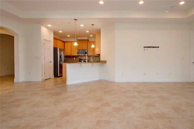 kitchen with stone counters, appliances with stainless steel finishes, decorative light fixtures, backsplash, and kitchen peninsula