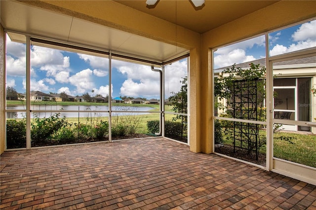 unfurnished sunroom with a water view and ceiling fan