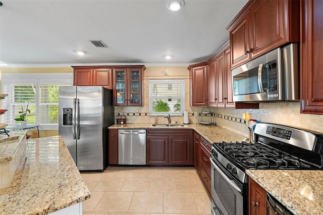 3887 50th Ave S, Saint Petersburg, FL 33711 - kitchen with appliances with stainless steel finishes, a sink, ornamental molding, plenty of natural light, and light stone countertops