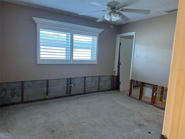 empty room with ceiling fan and a textured ceiling