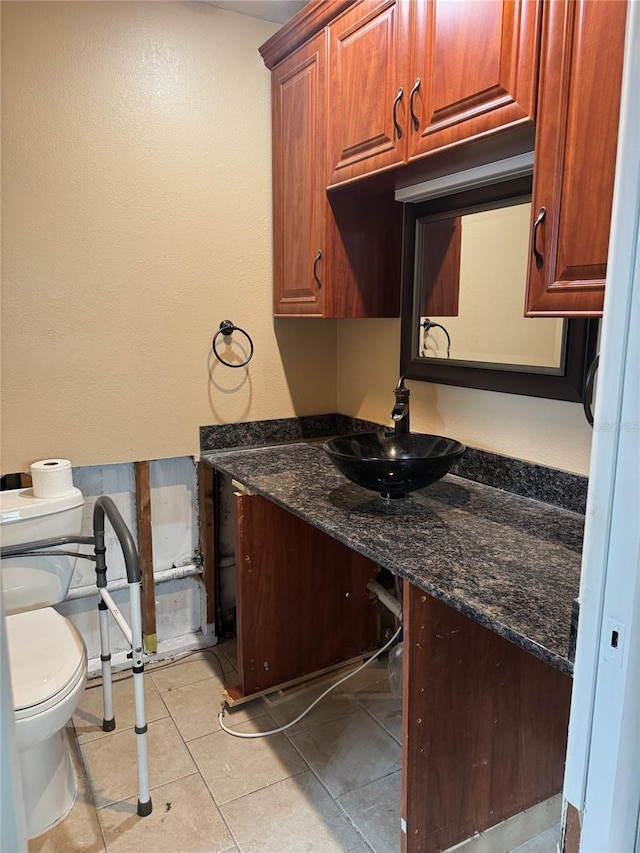 kitchen with light tile patterned floors, sink, and dark stone counters