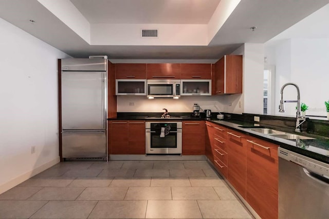 kitchen featuring appliances with stainless steel finishes, light tile patterned flooring, sink, and a raised ceiling